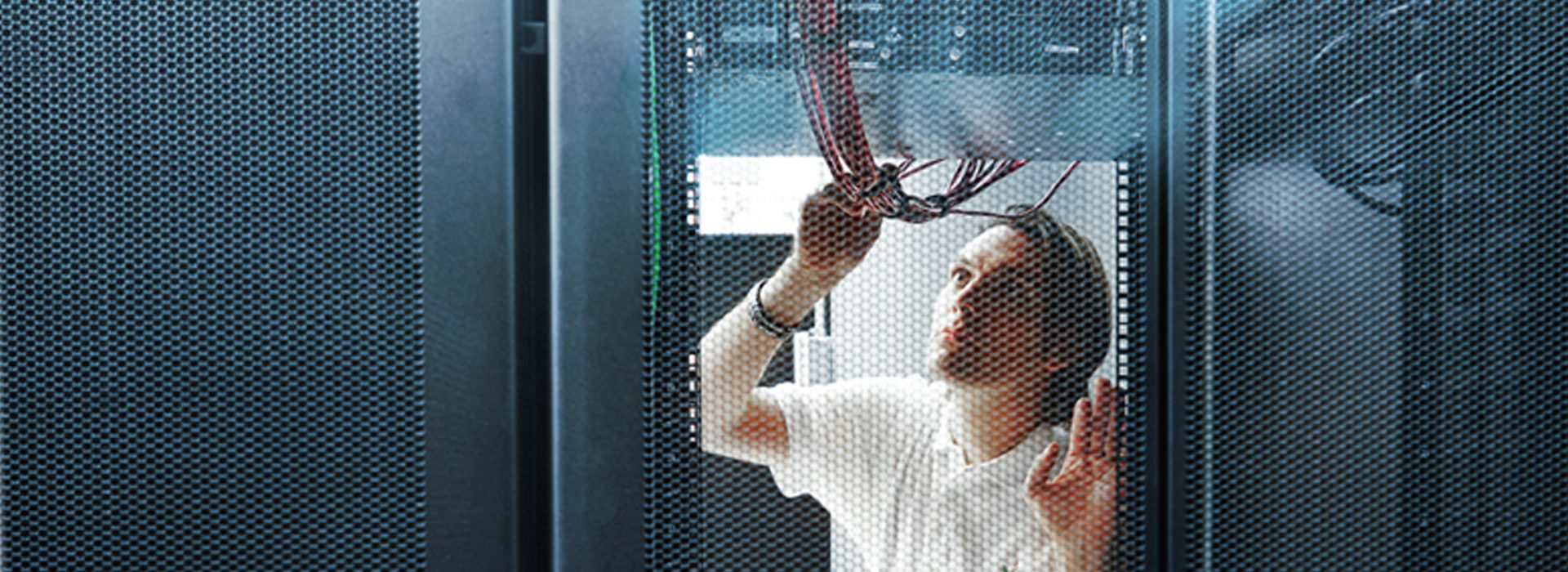 Close-up of an MGB Systems specialist examining wires in the server room of a data center